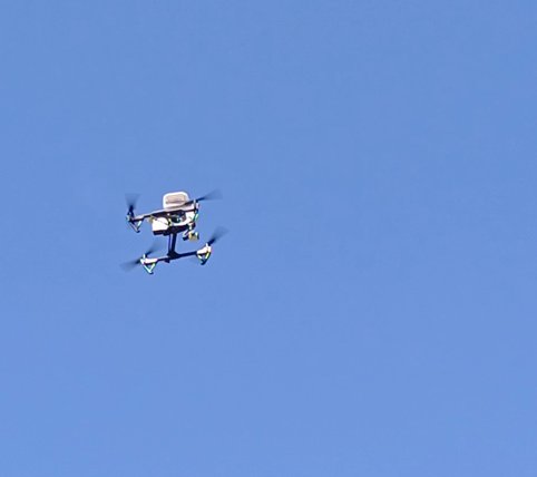The sensor drone airborne against clear blue sky.