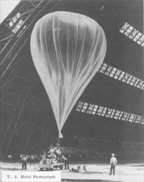 A transosonde weather balloon being inflated inside a hangar before launch, U.S. Navy photograph.